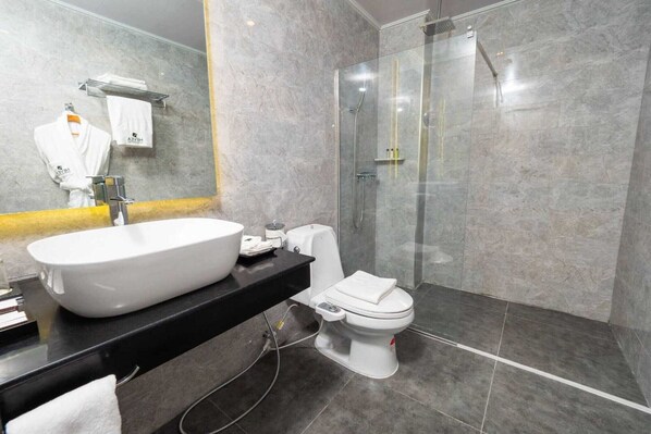 A modern bathroom with a large white sink, a toilet, and a glass-enclosed shower.