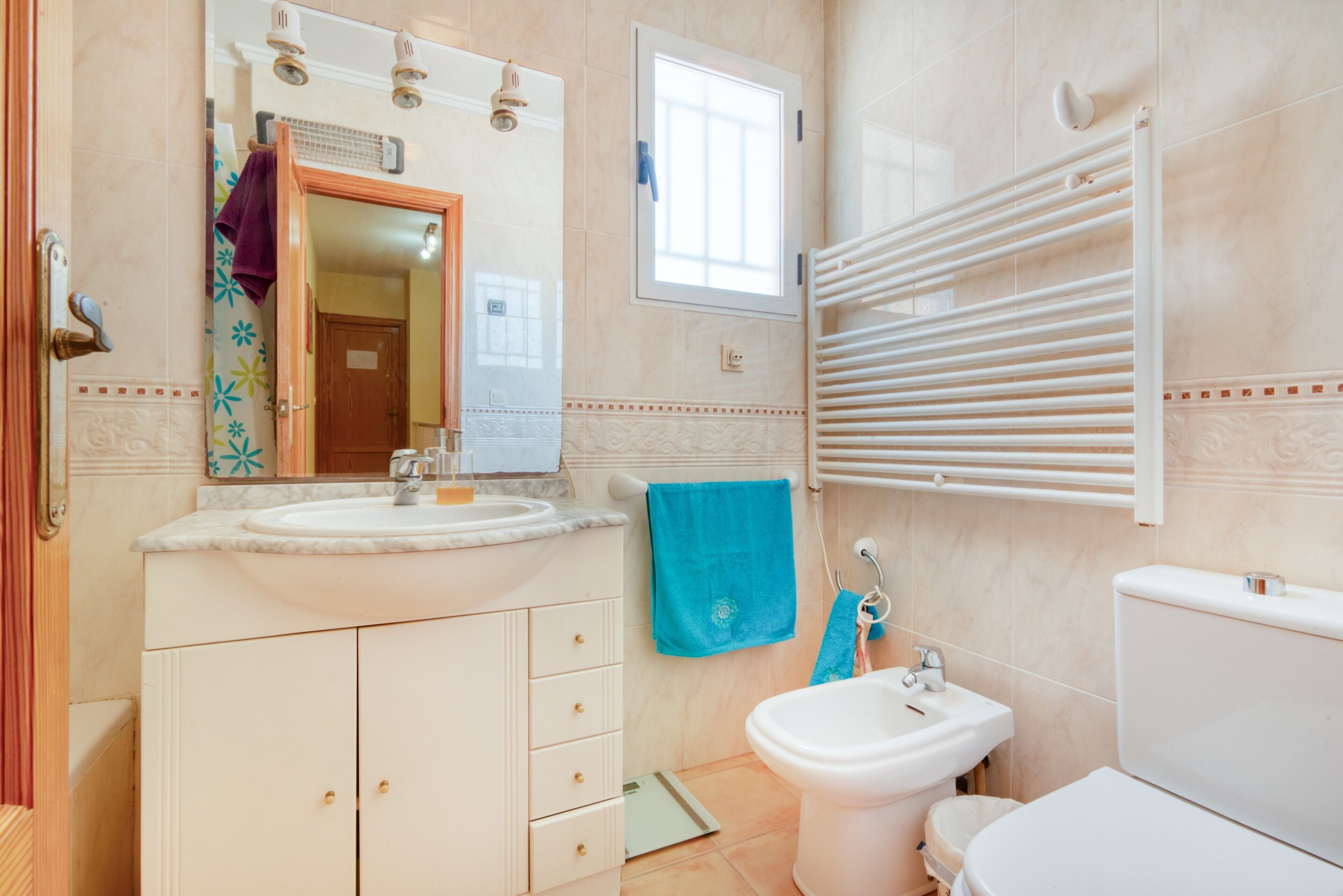 Une salle de bain équipée d’un lavabo, d’un miroir, d’un porte-serviettes et de toilettes.