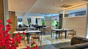 Un vestíbul d'hotel modern amb diverses zones de restauració, una taquilla d'eixida i una zona de seients amb un sofà.
