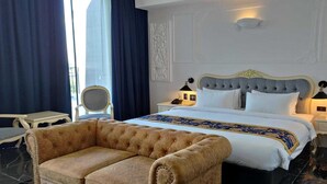 Une chambre d’hôtel avec un grand lit, deux tables de chevet, une chaise et un panneau décoratif au mur.