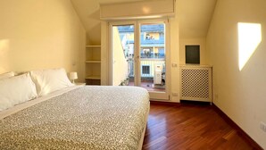 Une chambre avec un lit, une télévision, un balcon et une vue sur l’extérieur.