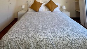 Une chambre à coucher comprenant un lit, deux tables de chevet, une armoire et une fenêtre.