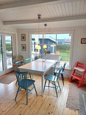 Een eethoek met een tafel en stoelen, een raam met uitzicht, en een rode stoel.