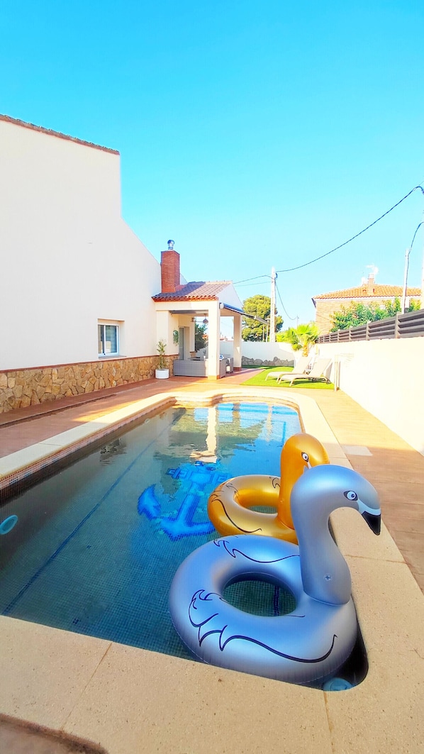 A swimming pool with inflatable swan and dolphin floats.