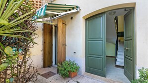 Un patio con una puerta de madera, una puerta verde y un toldo a rayas.