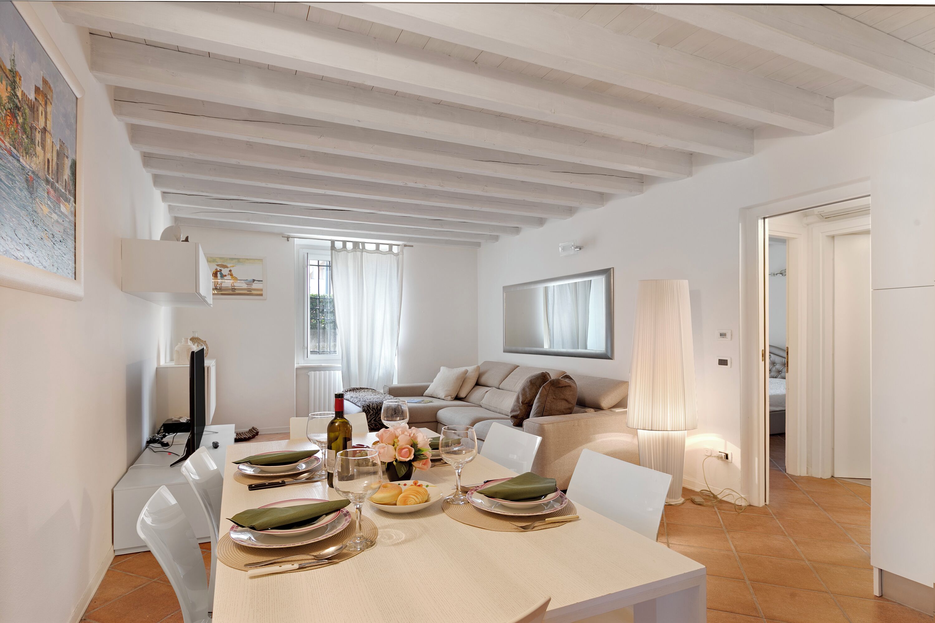 A dining area with a table set for four, a sofa, and a lamp.