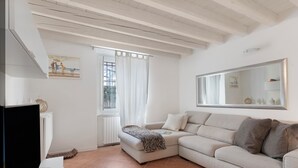 Una sala de estar con un sofá, un televisor, una ventana con cortinas y un cuadro en la pared.