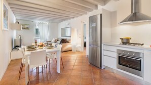 Una cocina moderna con armarios blancos, un refrigerador de acero inoxidable y un horno empotrado.
