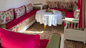 Ein Wohnzimmer mit einer Sofagarnitur, einem runden Tisch und einem an der Wand befestigten Fernseher.