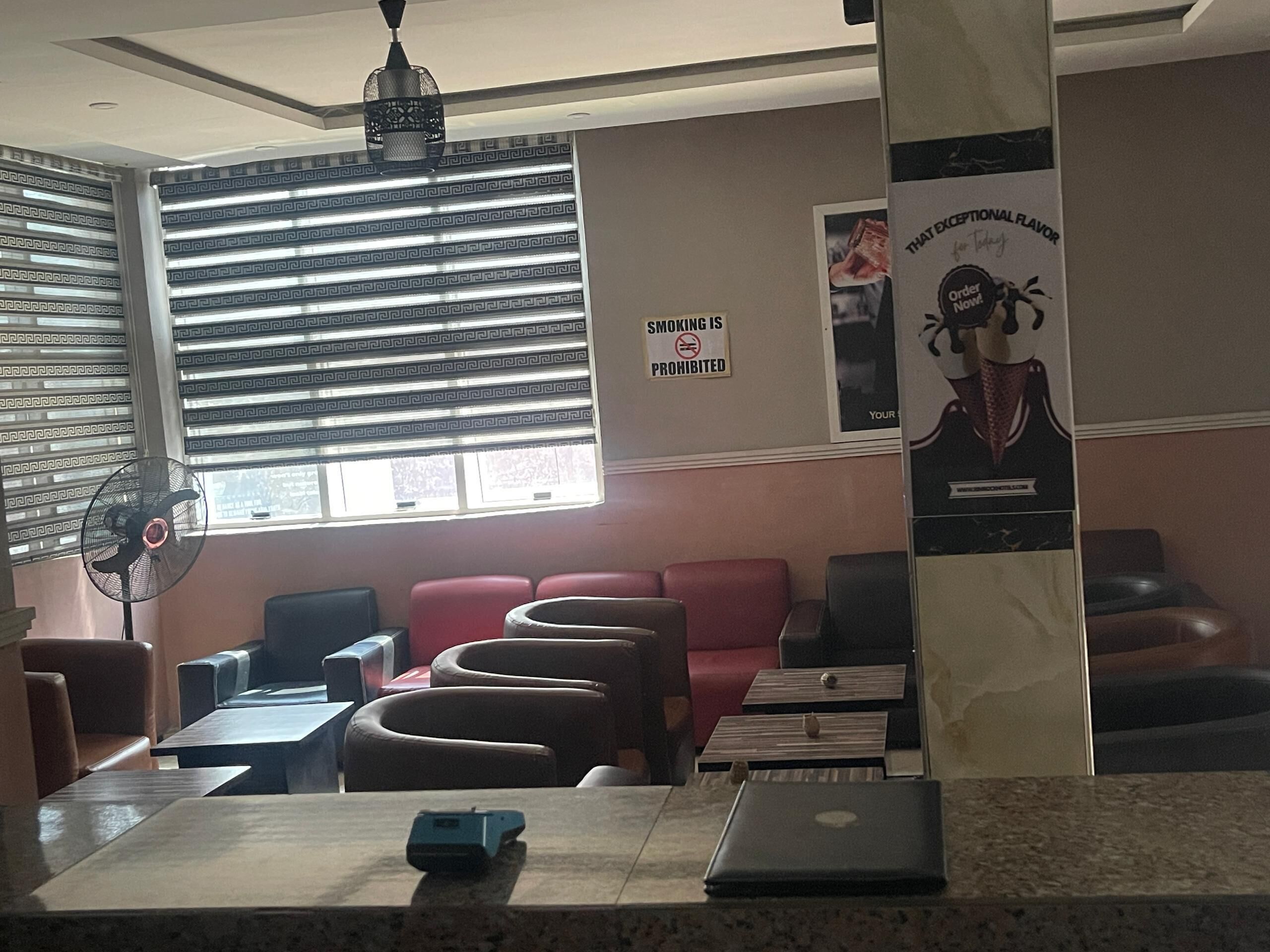 Zona salotto con ventilatore, un portatile e un poster appeso al muro.