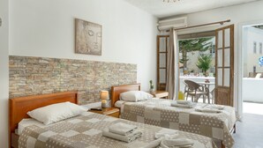 Une chambre d’hôtel avec deux lits, un mur en pierre, une tête de lit en bois, un tableau et une vue sur l’extérieur.