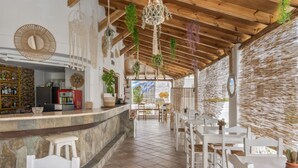 Ein Restaurant mit einer Steintheke, weißen Stühlen, hängenden Pflanzen und einer Holzzahl.