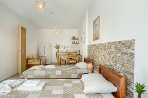 Une chambre à coucher comprenant un lit, une table de chevet, une lampe et donnant sur un coin cuisine.