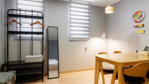A room with a bunk bed, a desk, and a dining table with chairs.