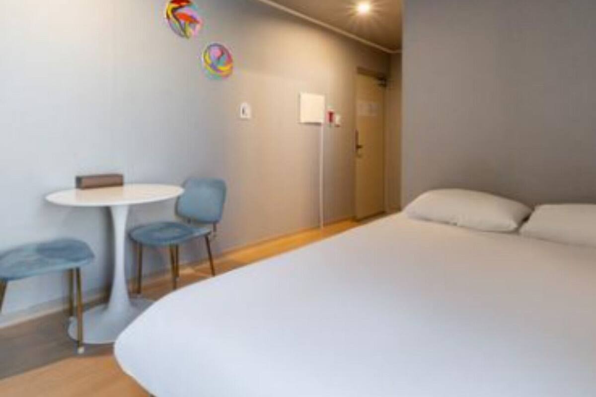 Une chambre d’hôtel moderne avec un grand lit, une petite table ronde avec des chaises et une porte.