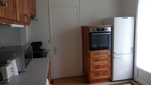 Una cocina compacta con armarios de madera, horno empotrado, refrigerador y microondas.
