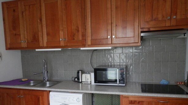Una cocina con armarios de madera, lavadora, microondas, tostadora y un fregadero.