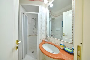 Een badkamer met een douche, wastafel en spiegel.