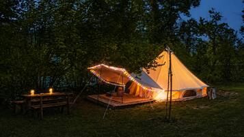 A tent with a platform and a table, surrounded by trees.
