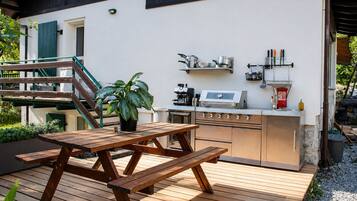 An outdoor kitchen with a grill, a sink, and a potted plant.