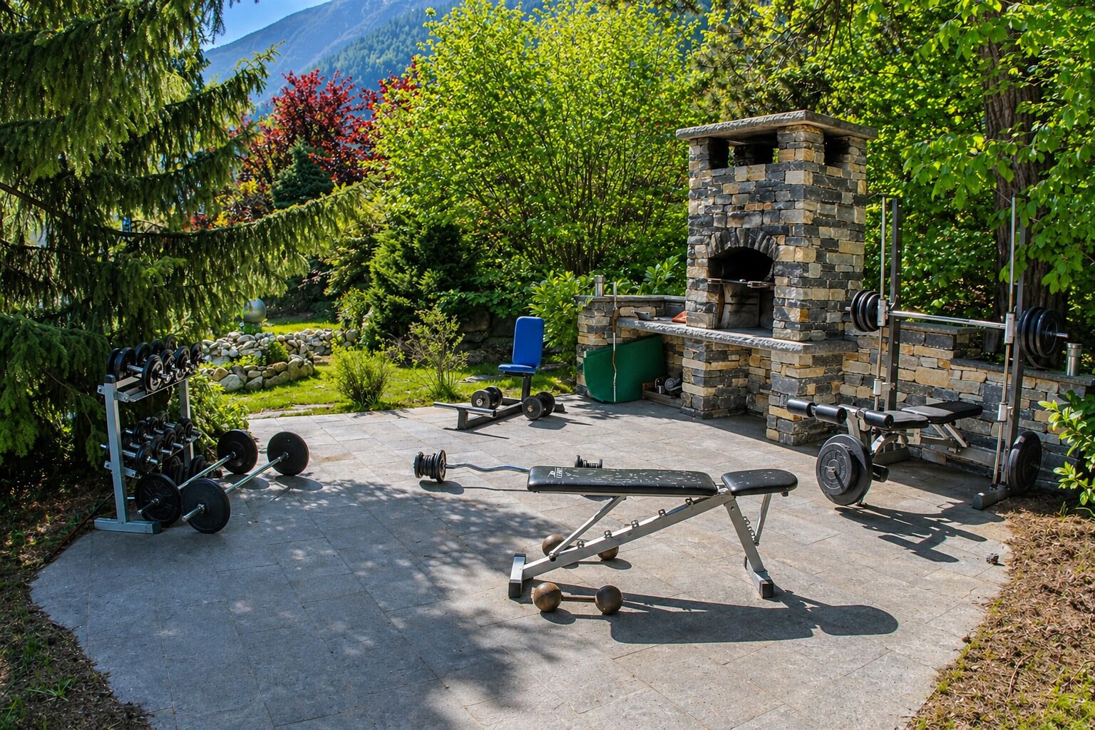 An outdoor gym with a stone fireplace, weightlifting equipment, and a bench press.