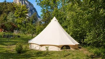 A white tent-like structure in a grassy area with a mountain in the background.