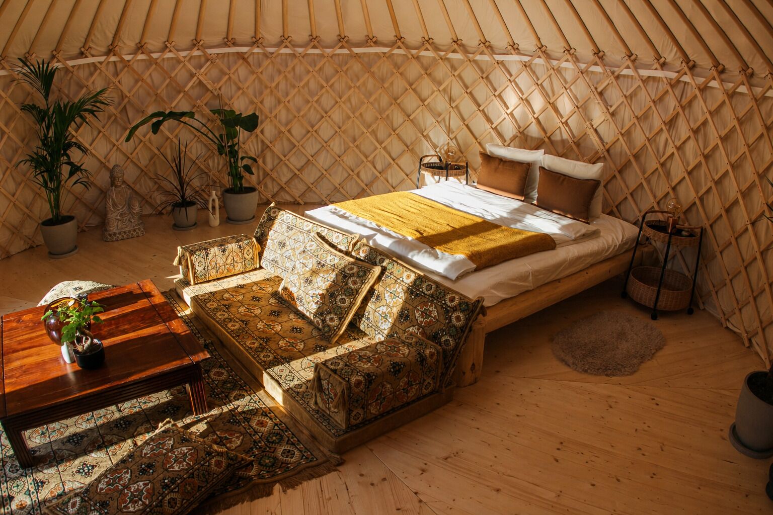 A cozy, well-lit tent with a bed, seating area, and potted plants.