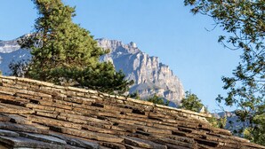 Eine Blockhütte mit Kamin aus Stein, einem Esstisch mit Stühlen und Blick auf Berge.