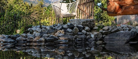 Une cabane en bois avec un mur en pierre et un hamac.