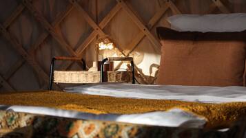 A cozy room with a bed, a wicker chair, a hanging light, and a wooden wall.