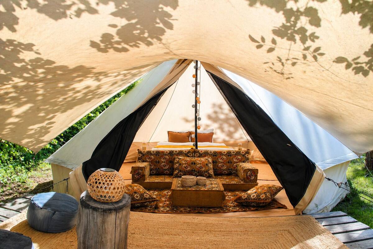 Una carpa con cama, almohadas y una lámpara colgante.
