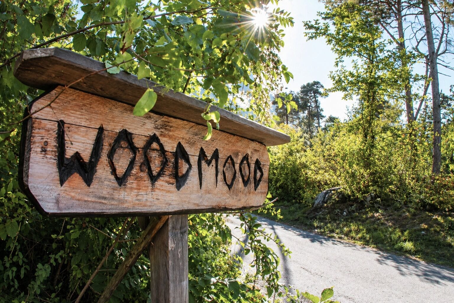 Un letrero de madera con el nombre 'WOODMOOD' pintado en negro.