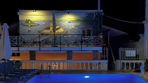 Una piscina con vistas a un edificio que tiene un mural, un puesto de salvavidas y una barandilla.