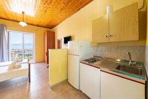A compact kitchen with a wooden ceiling, a refrigerator, a sink, and a window with a view. - Studio 'Gavriil G4' with Sea View, Wi-Fi and Air Conditioning (Corfu)
