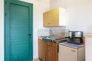 Une cuisine avec une porte de couleur turquoise, des meubles en bois, un évier et une machine à café.