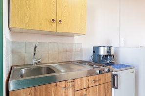 A kitchen with wooden cabinets, a stainless steel sink, a coffee machine, and a refrigerator. - Studio 'Gavriil G5' with Sea View, Wi-Fi, and Air Conditioning (Corfu)