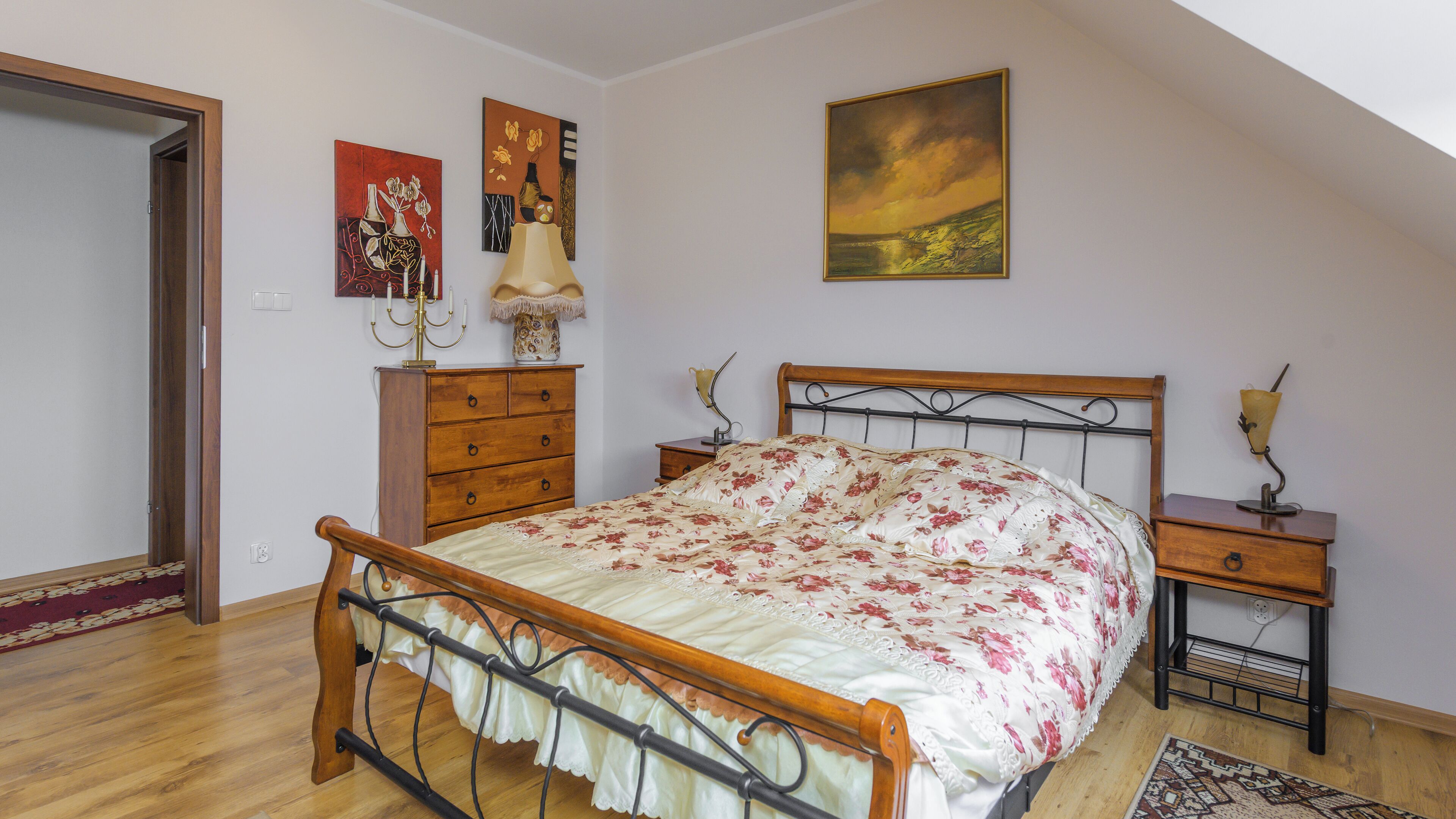 Un dormitorio con una cama de madera, una mesita de noche, un aparador y un cuadro en la pared.