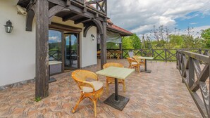 An outdoor patio with wicker furniture and a stone-tiled floor. - Willa Sun & Snow Zasypane Mazury (gmina Malkinia Gorna)