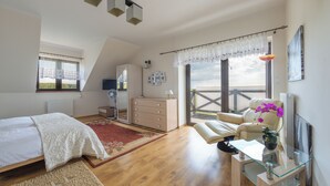 A bedroom with a bed, a dresser, a desk with a chair, a radiator, and a balcony with a view. - Willa Sun & Snow Zasypane Mazury (gmina Malkinia Gorna)