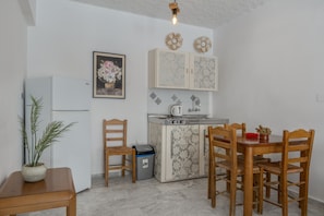 Une cuisine de taille réduite comprenant un réfrigérateur, un évier et une table à manger avec des chaises.
