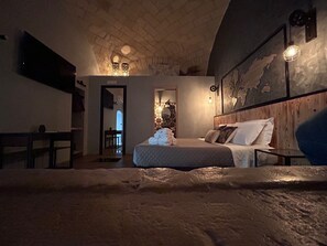 A cozy bedroom with a stone ceiling, a bed with a quilt, and a wooden headboard. - The Prince's Mansion (Trani)