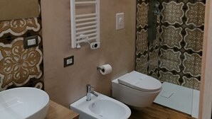 A modern bathroom with two sinks, a bidet, a shower, and patterned tiles. - The Prince's Mansion (Trani)