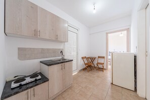 A compact kitchen with a built-in stove, a sink, and wooden cabinets. There is a dining area with a table and chairs.