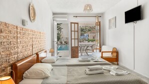A hotel room with two beds, a TV, a pool view, and a dining area.