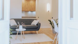 A modern living room with a grey sofa, a small white table, and a white chair. - Stylish Balcony Apt on Stefan Cel Mare Blvd (Chișinău)