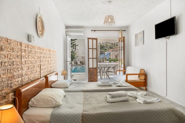 A hotel room with two beds, a TV, a pool view, and a dining area.