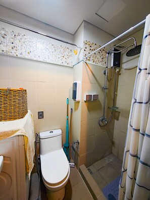 Une petite salle de bain avec des toilettes, une douche et un lavabo.