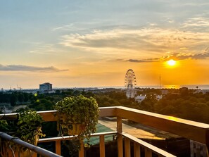 A balcony with a view of a Ferris wheel and sunset.