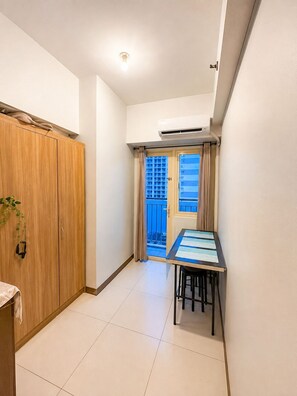 Una habitación con un armario de madera, una mesa con sillas y un ventanal con cortinas.