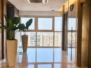 Un interior moderno con ventanas amplias, una planta en maceta y una vista despejada del paisaje urbano.